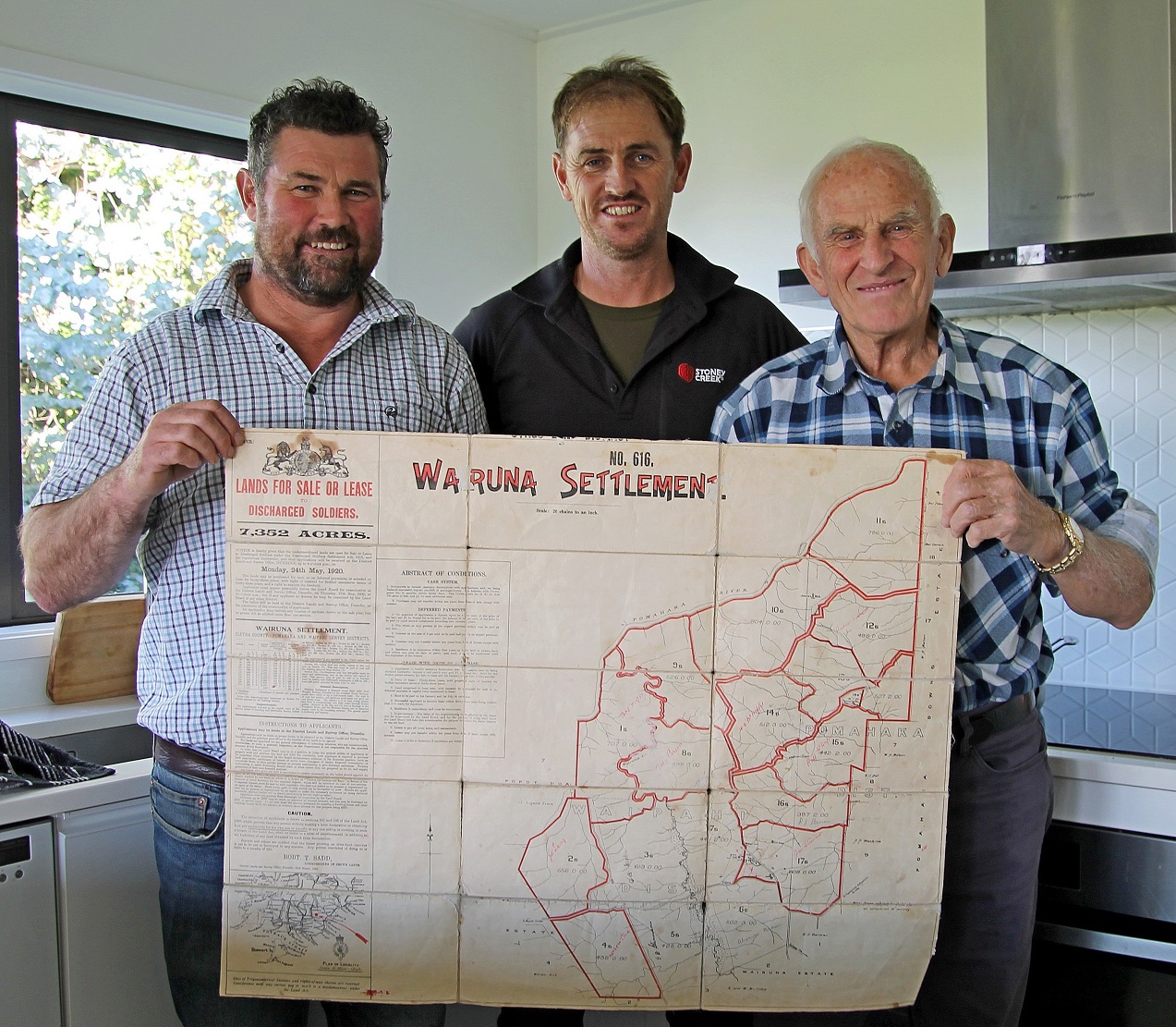 Terry McHaffie (left), his cousin Leigh and uncle Peter hold the original cloth map of Wairuna...
