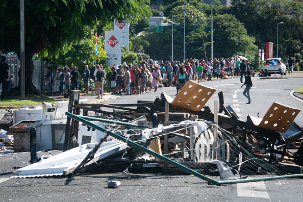 People wait in line to buy provisions from a supermarket in the Magenta district of Nouméa. Photo...