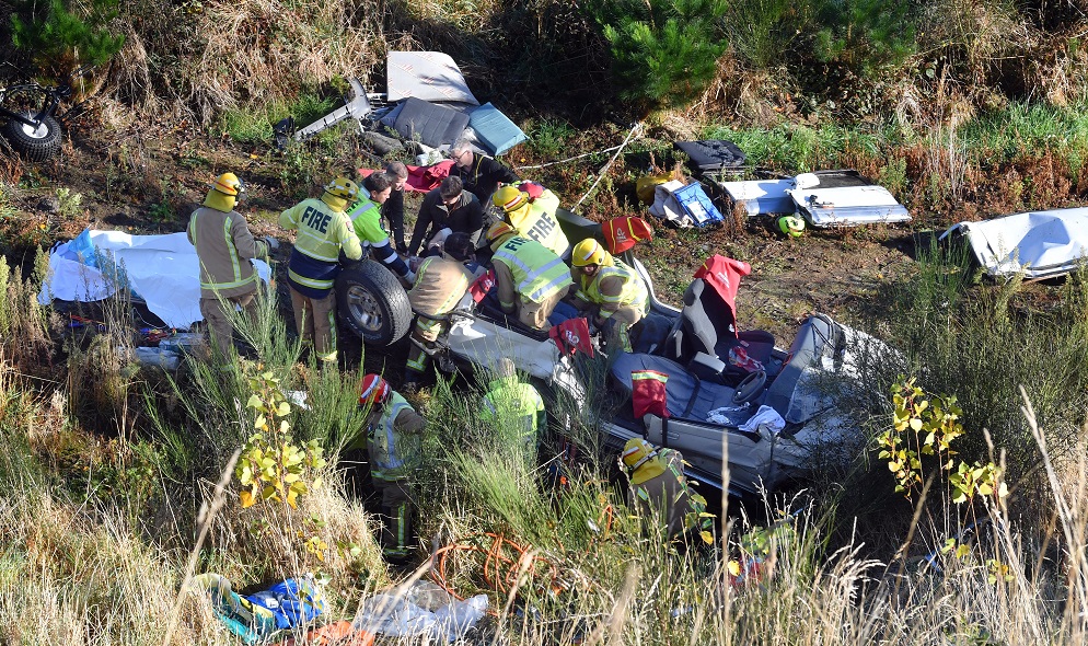 Emergency services personnel swarm over a vehicle that slid off State Highway 1 and 40m down a...