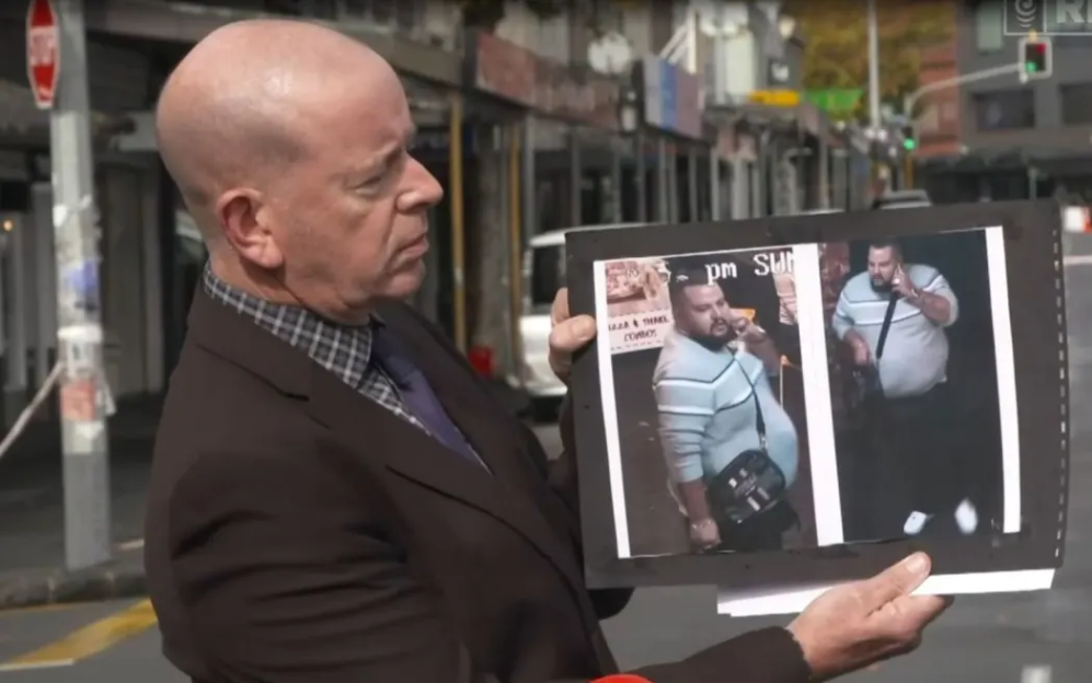 Detective Inspector Chris Barry holds an image of a man he says police are seeking in connection...