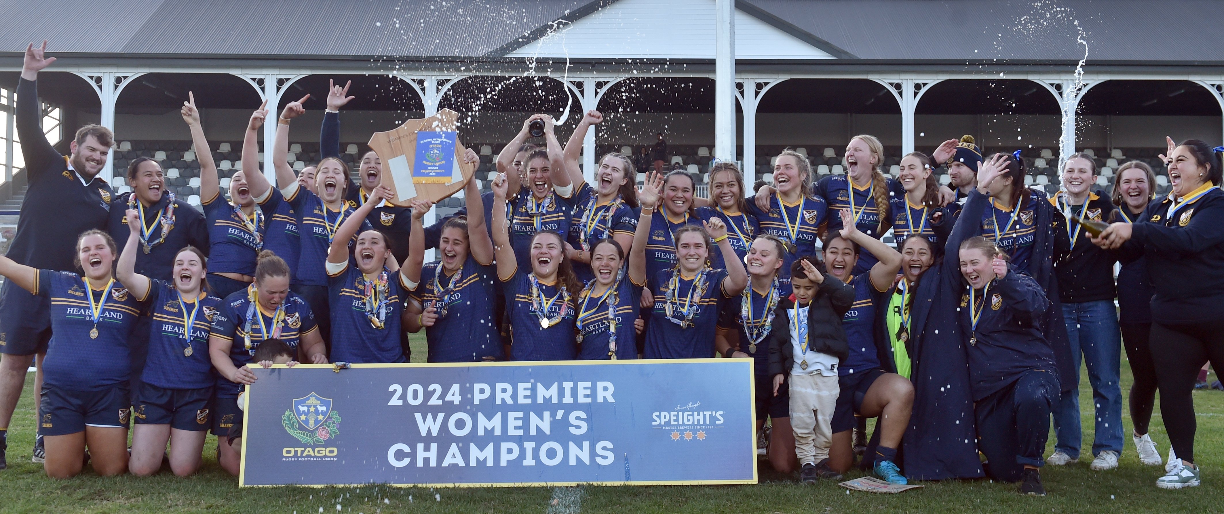 The Dunedin players and support staff celebrate with the spoils after the side’s win over...