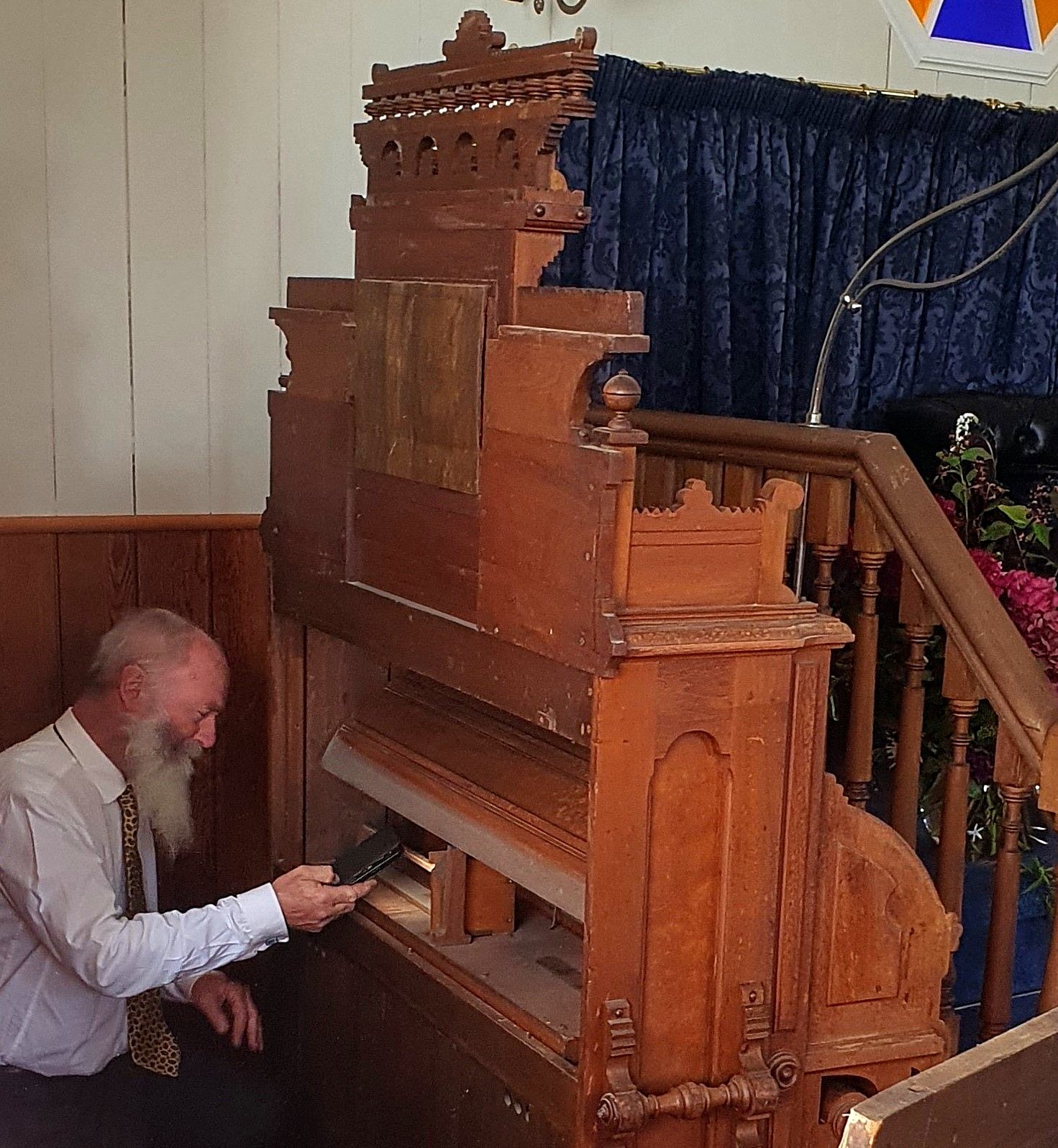 Herbert-based organ builder Dr Ron Newton inspects the Estey reed organ at Pukehiki Church during...