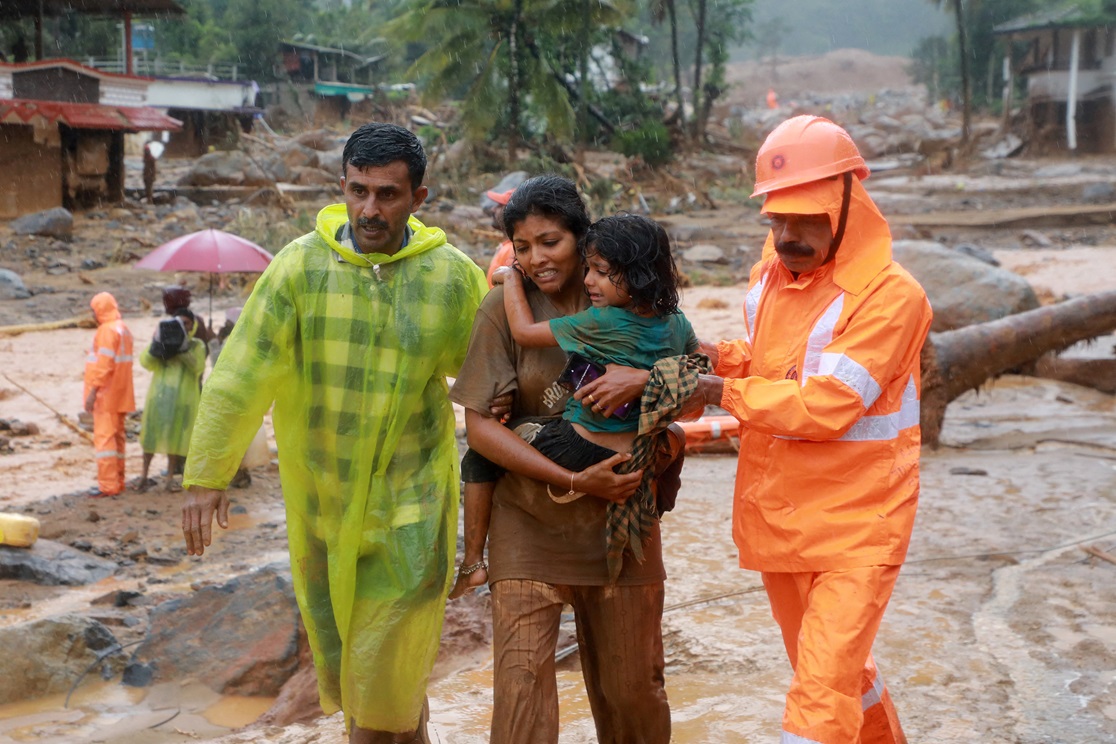 Rescuers help residents move to safety after landslides in the hills in Wayanad, in the southern...