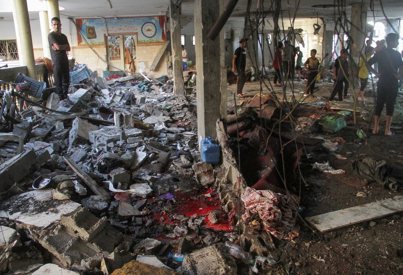 Palestinians survey damage at the site of an Israeli strike on a school sheltering displaced...