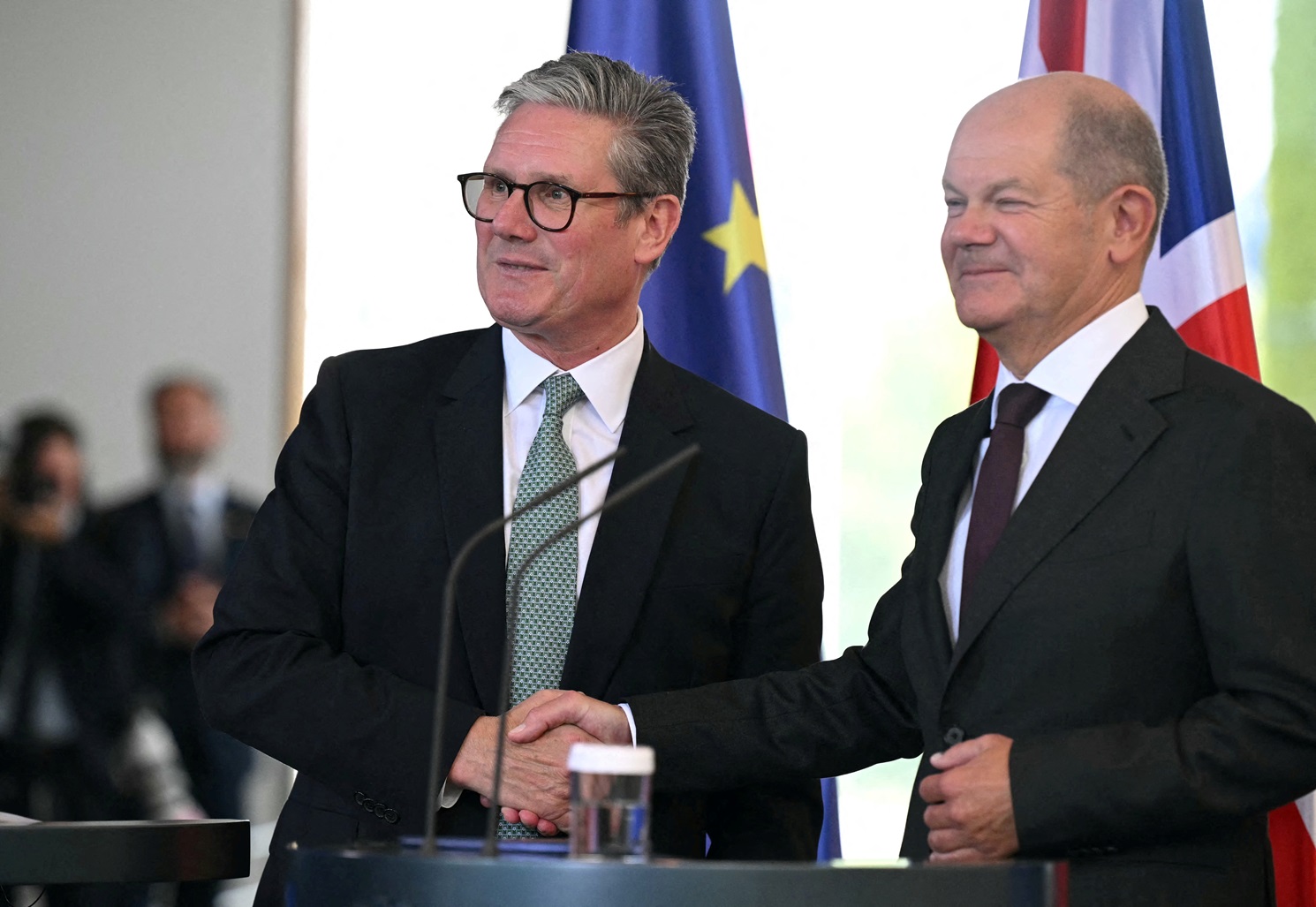 Britain's Prime Minister Keir Starmer (L) and German Chancellor Olaf Scholz shake hands at the...