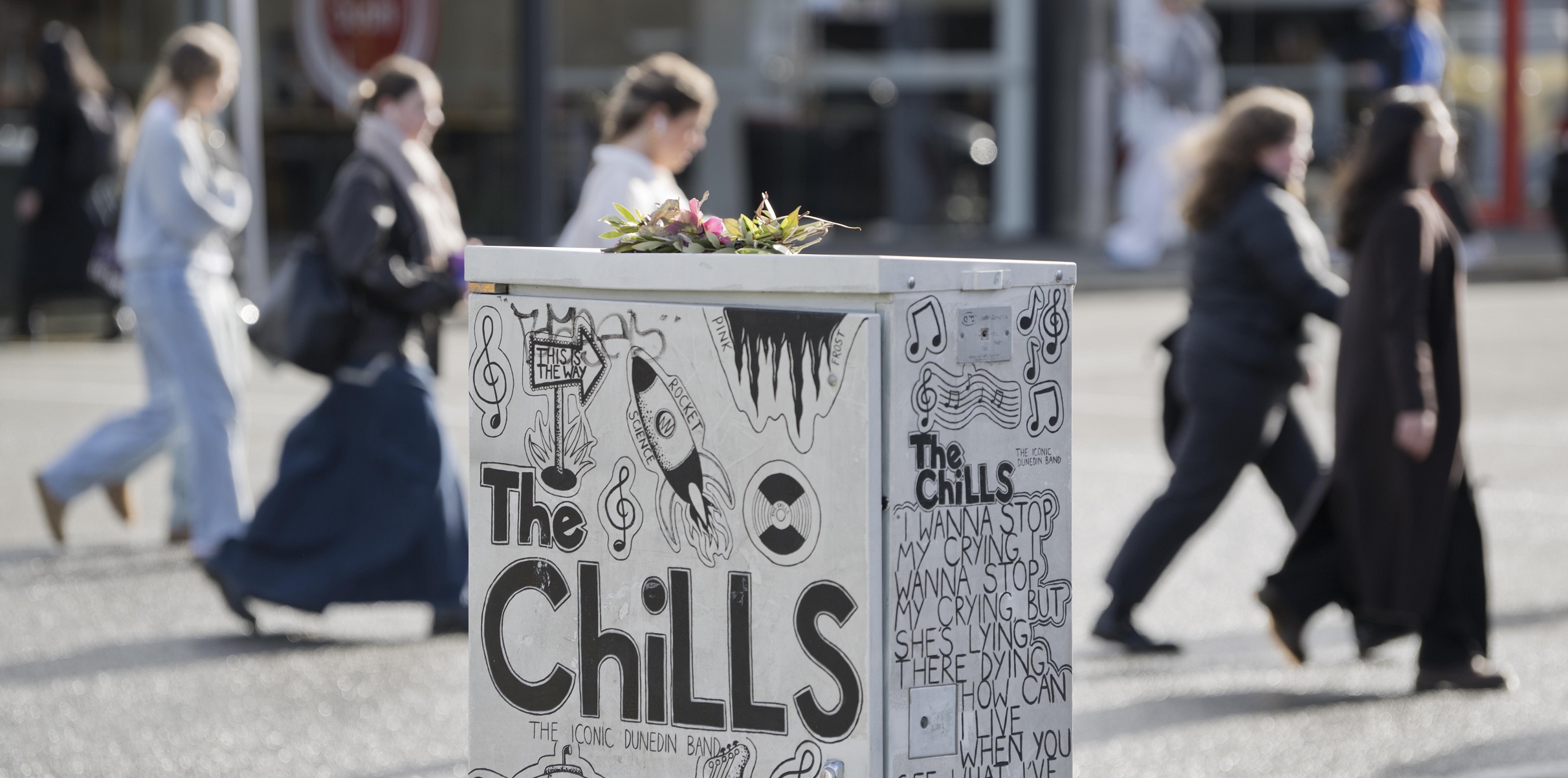 A floral posy placed on a traffic-control box featuring a tribute to Dunedin band The Chills in...