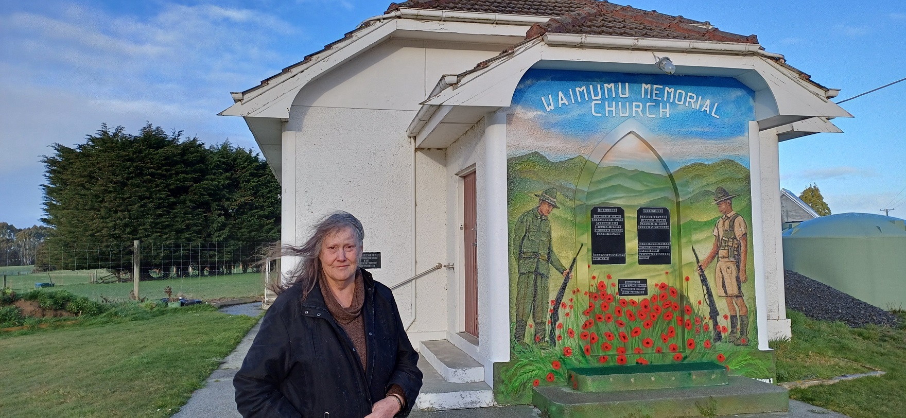 Waimumu Memorial Church owner Lana McMillan stands beside the mural her nephew spray-painted on...