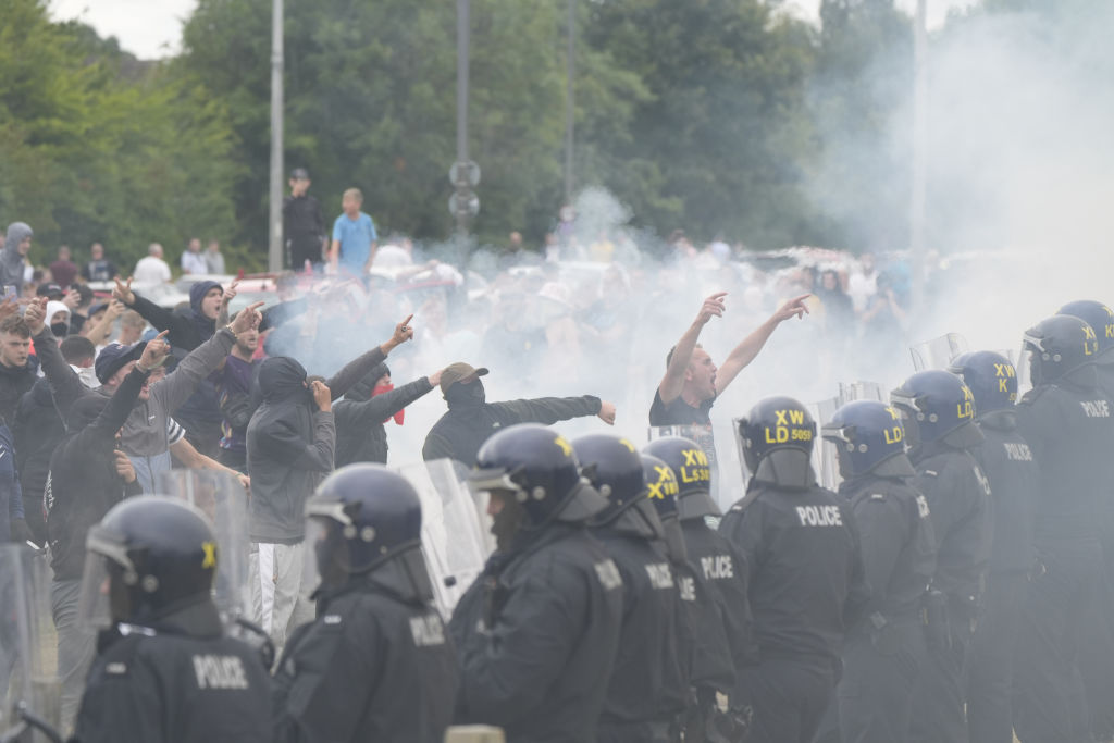 Police officers face protesters during an anti-immigration demonstration outside the Holiday Inn...