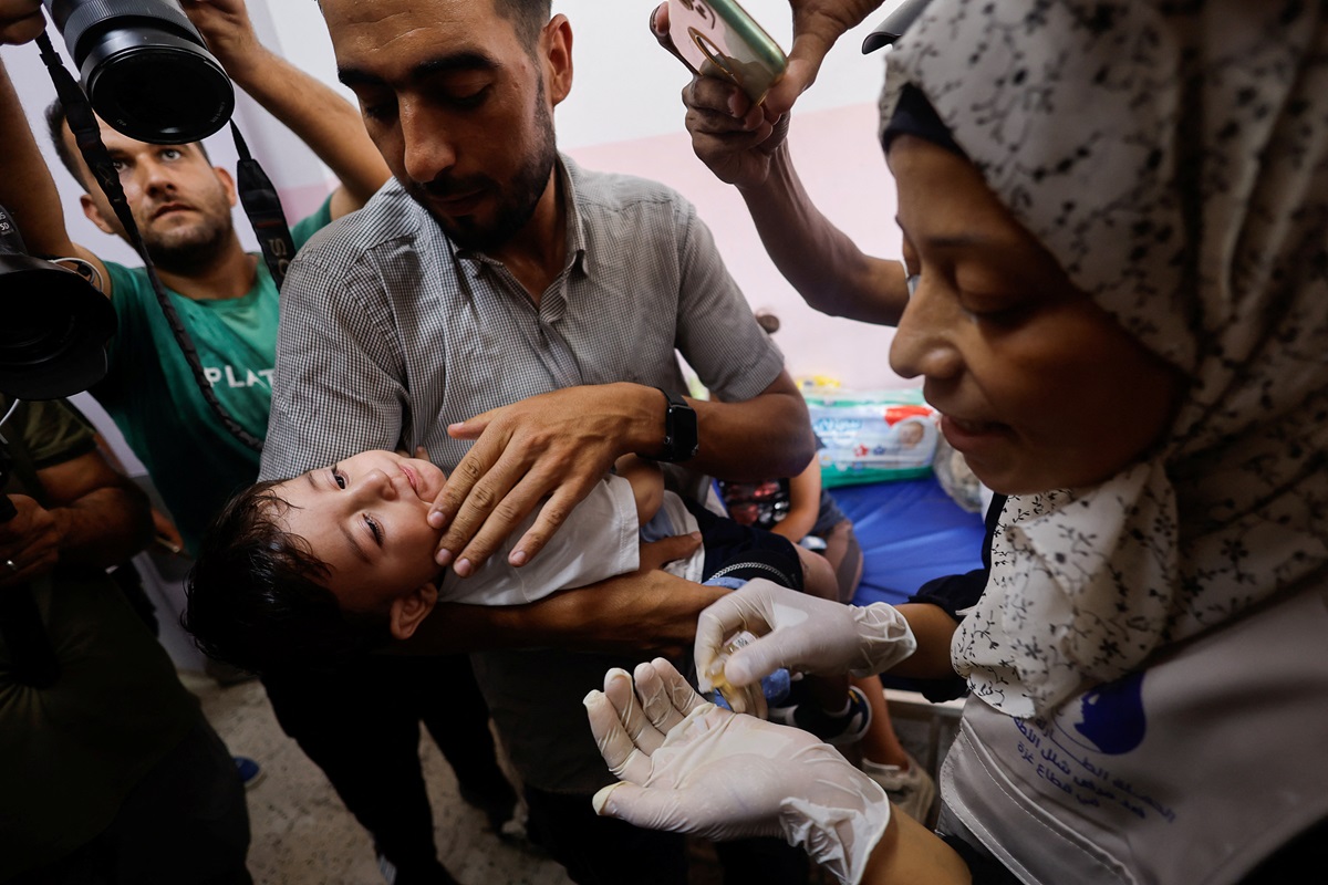 A Palestinian man holds a child being vaccinated against polio at Nasser hospital in Khan Younis...