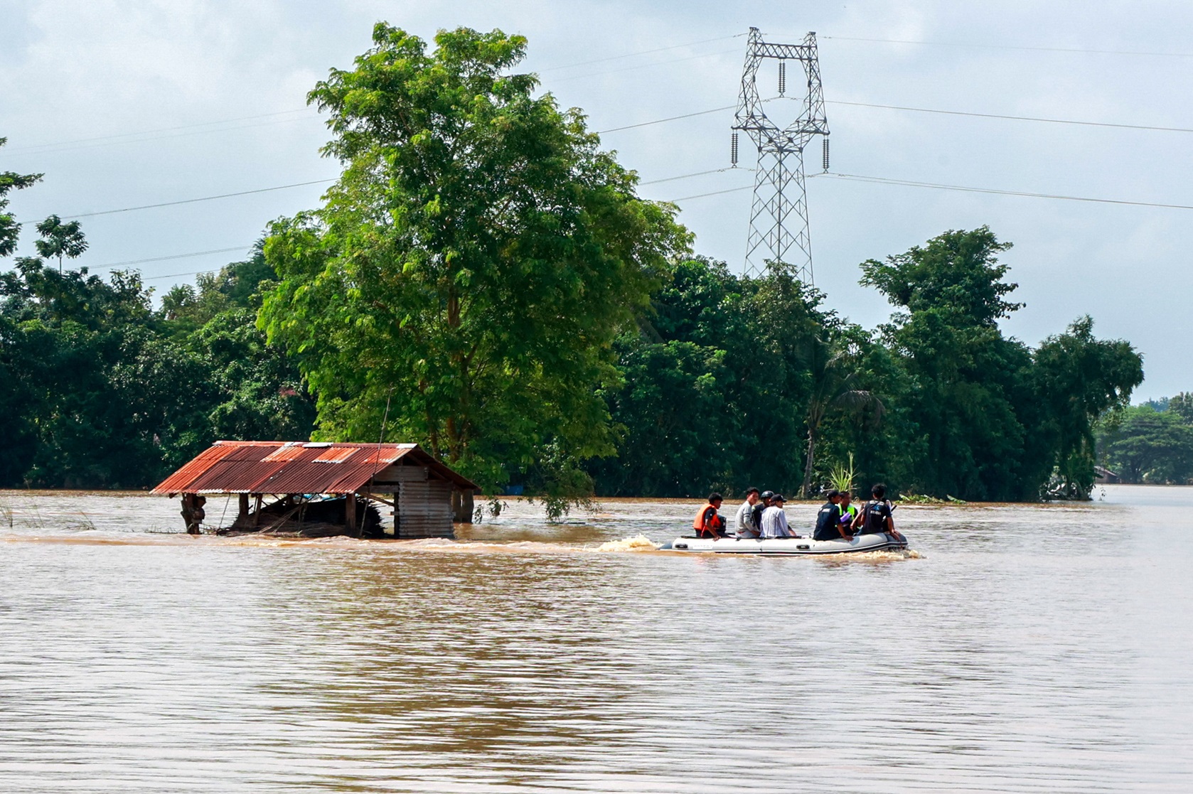 Rescuers ride a boat through a flooded area, searching for stranded people in Taungnoo city,...