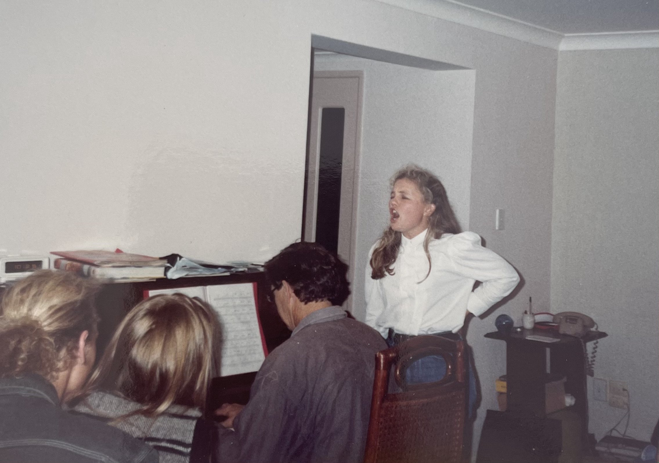 A young Arlie McCormick belts out a tune as her dad plays the piano. Photo: supplied