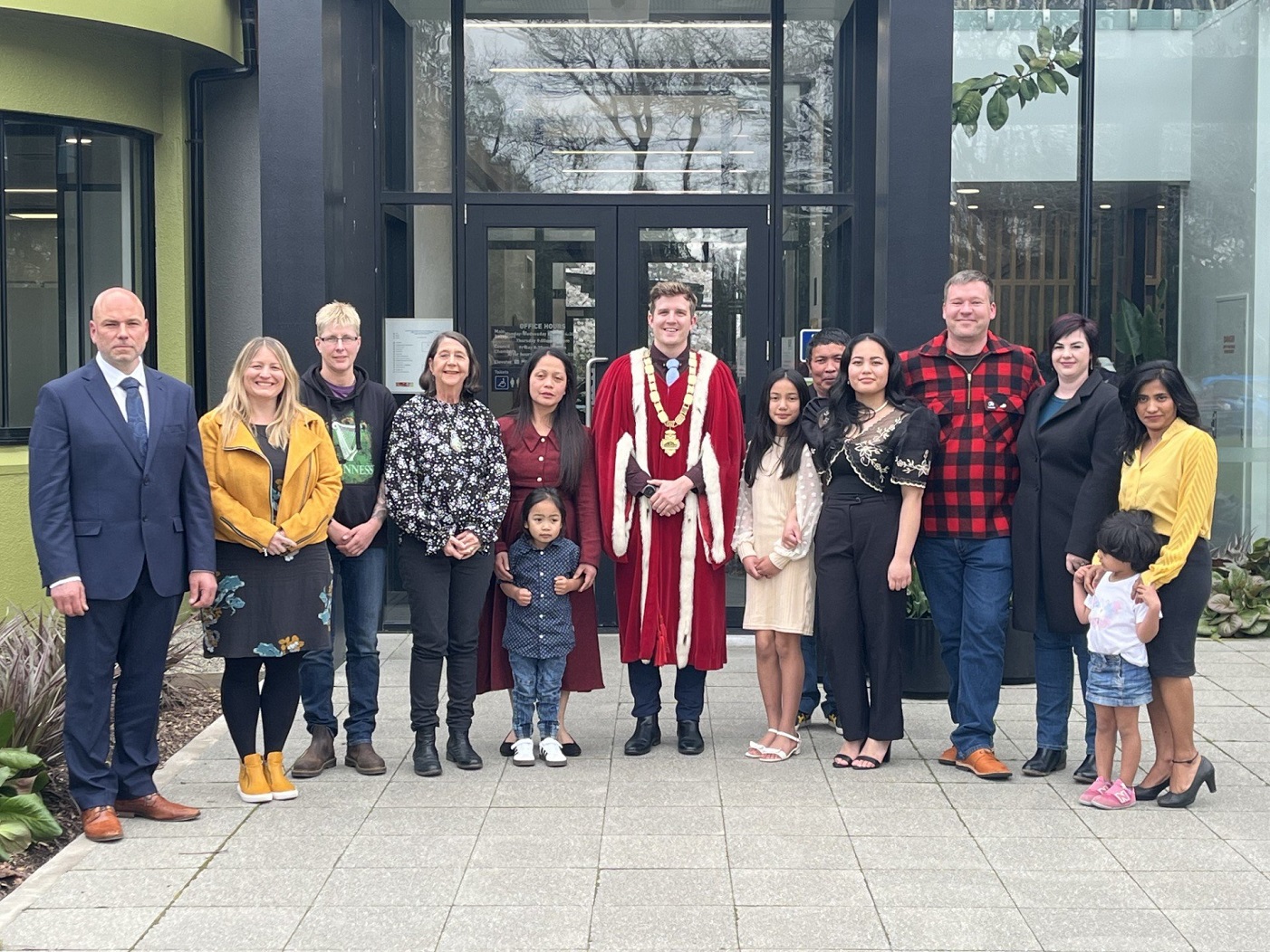 The new New Zealand citizens and their families celebrate with Mayor Ben Bell outside the Gore...