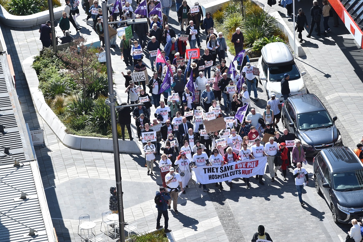 A huge crowd walks down George St towards the Octagon last Saturday to protest planned cuts to...