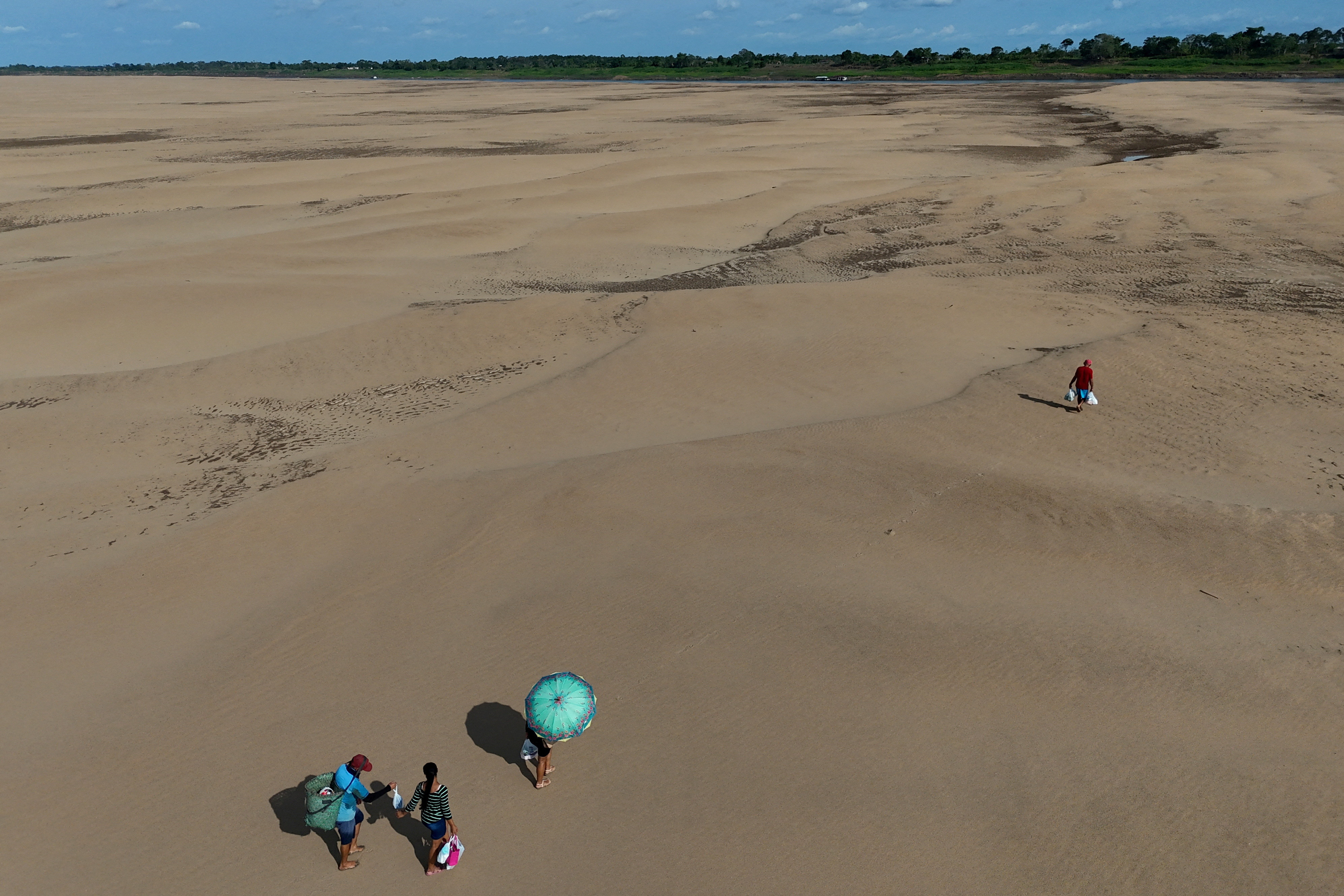 A drone view shows people carrying food and water to their isolated communities over sandbanks...