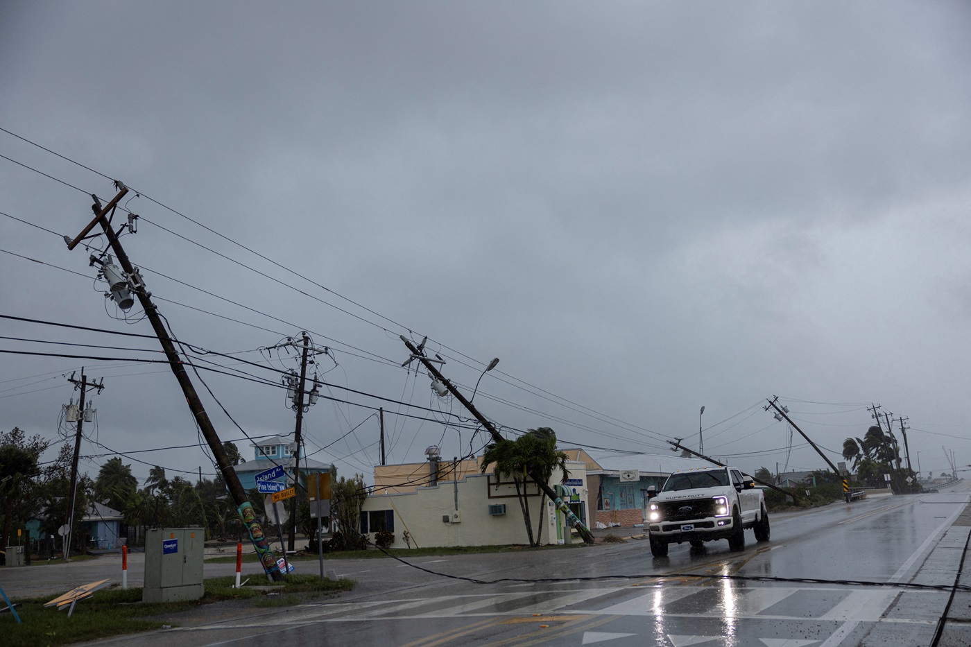 A motorist drives past broken utility poles downed by wind gusts as Hurricane Milton approaches...