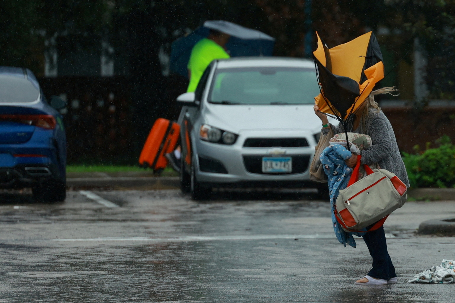 A woman with a buckled umbrella arrives at a shelter in Lakeland, Florida as Hurricane Milton...