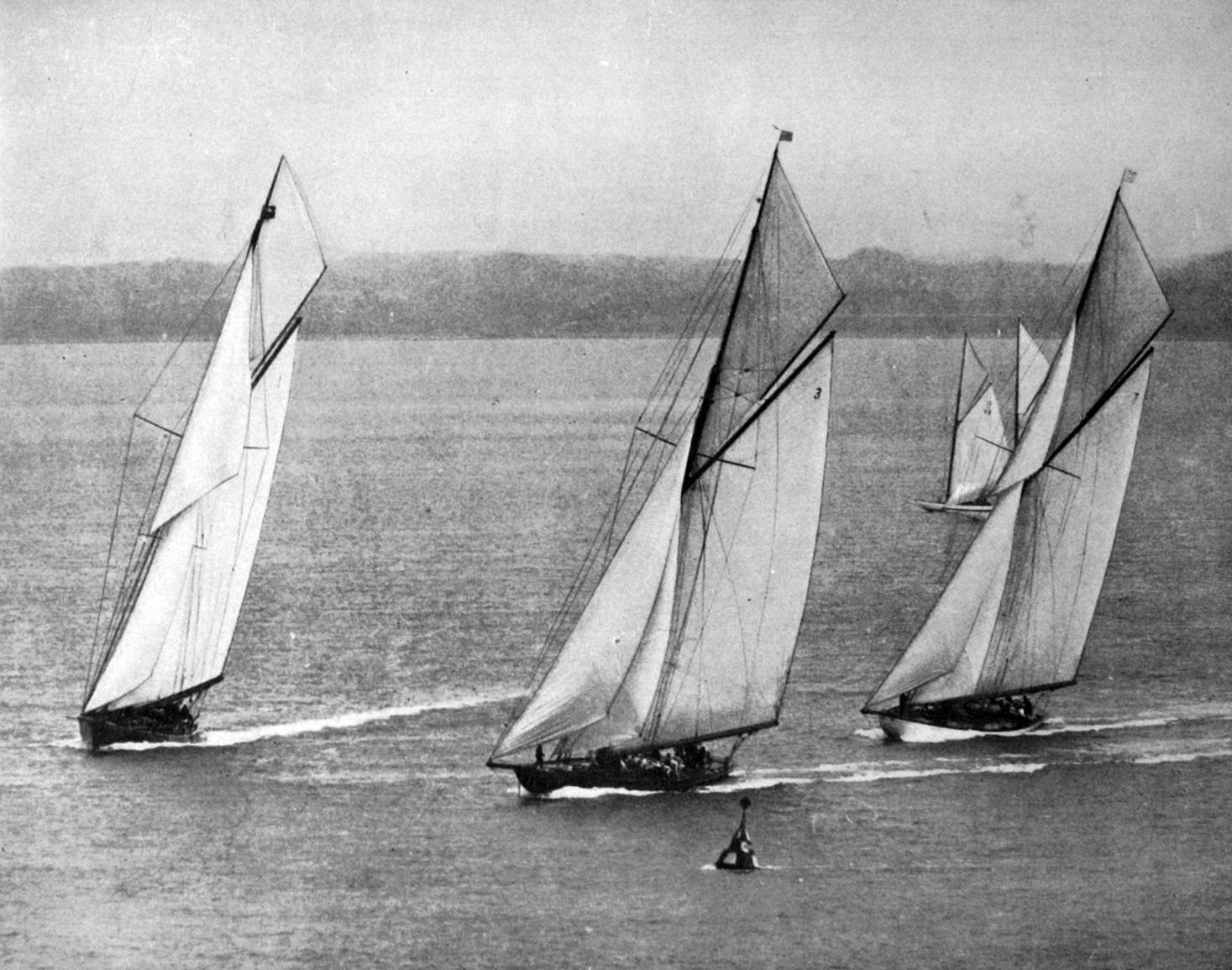 King George V’s yacht Britannia crosses the line at Cowes, Isle of Wight, followed by Shamrock...