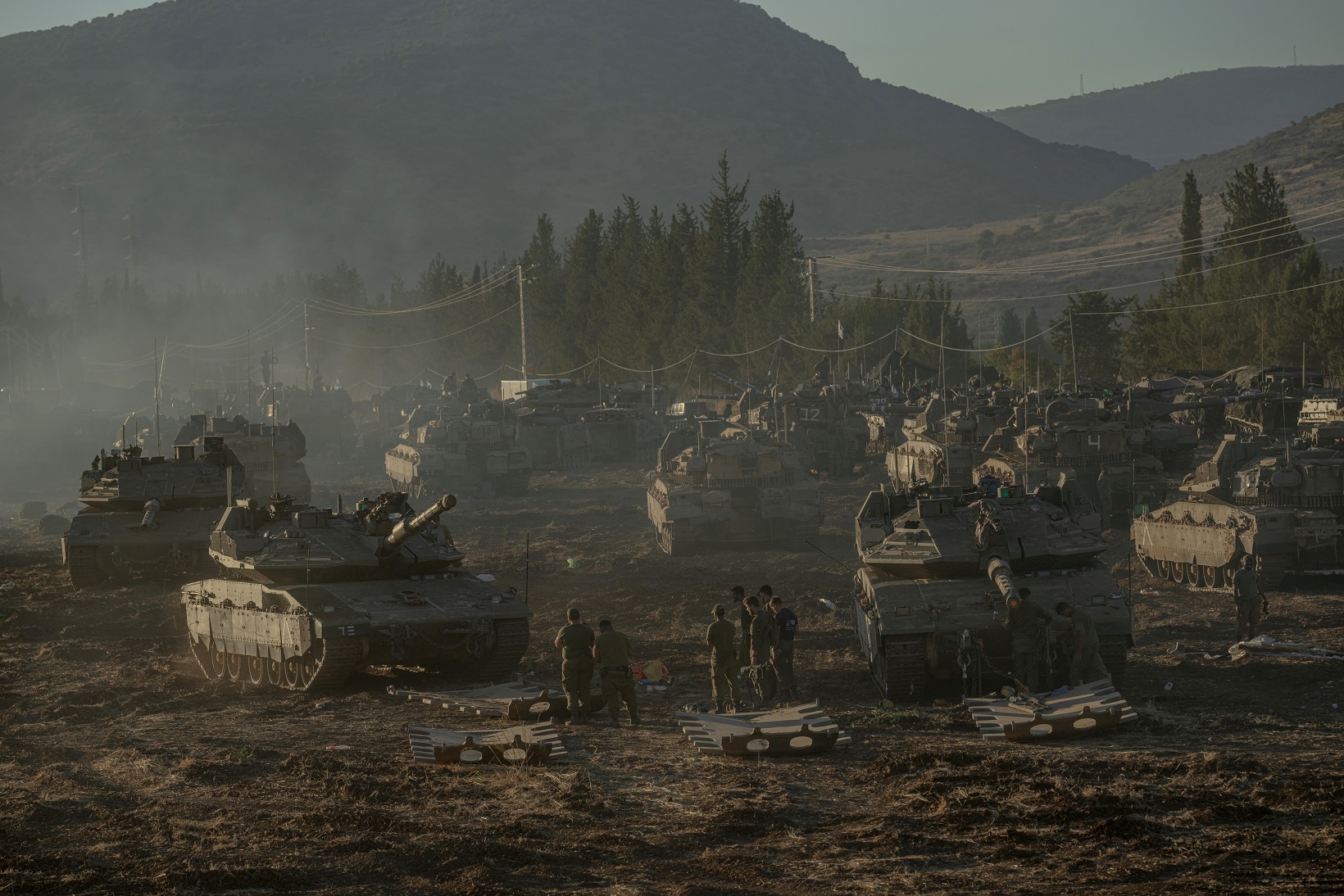 Israeli tanks and armoured personnel carriers mass at the Israeli-Lebanese border yesterday as...