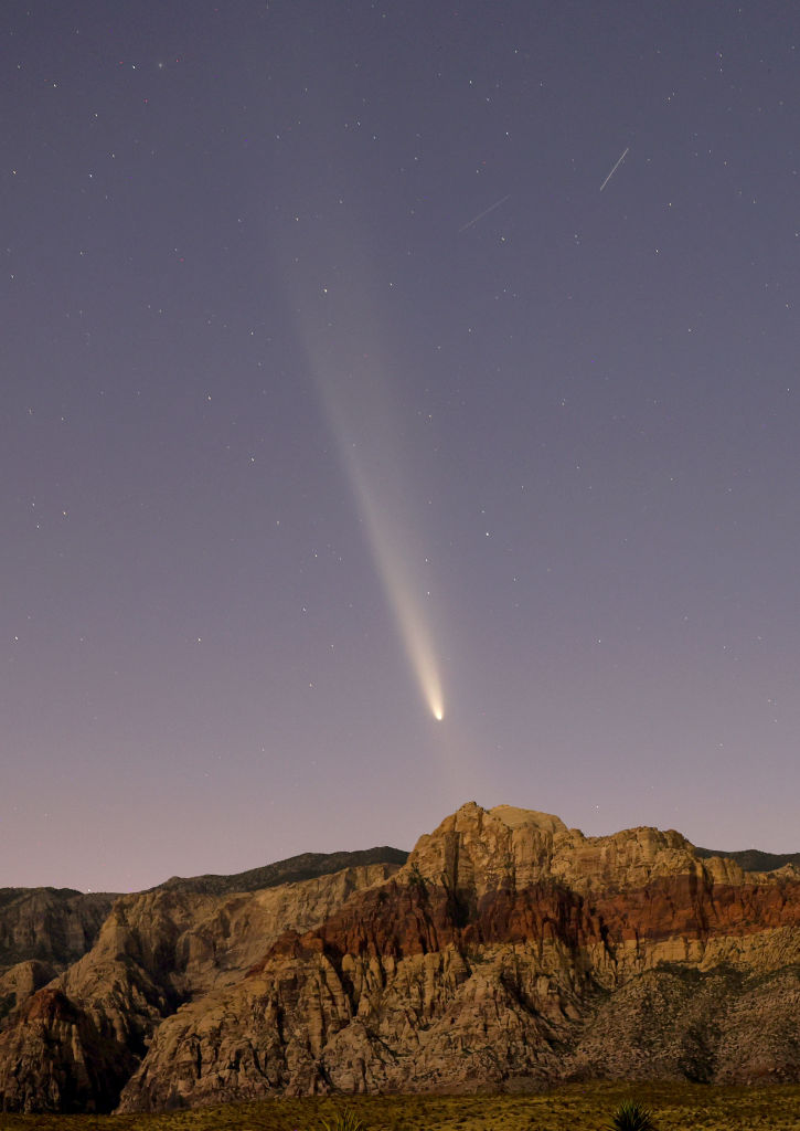 Comet C/2023 A3 appears in the western sky shortly after sunset above rock formations in the Red...