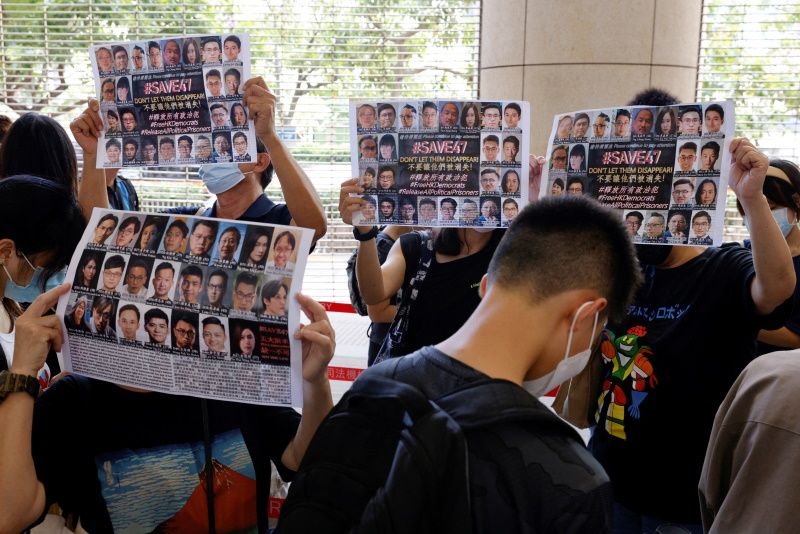 Supporters hold up placards among people queuing up at the West Kowloon Magistrates' Courts for...