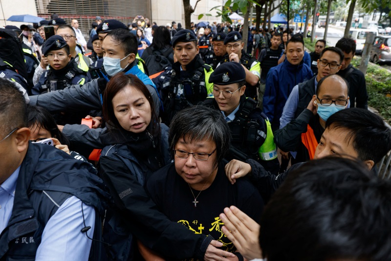 A woman is taken away by police to search outside the West Kowloon Magistrates' Courts building,...