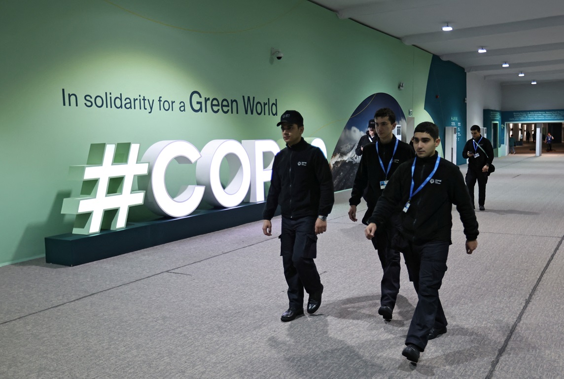 People walk past the logo of COP29 United Nations climate change conference in Baku, Azerbaijan....