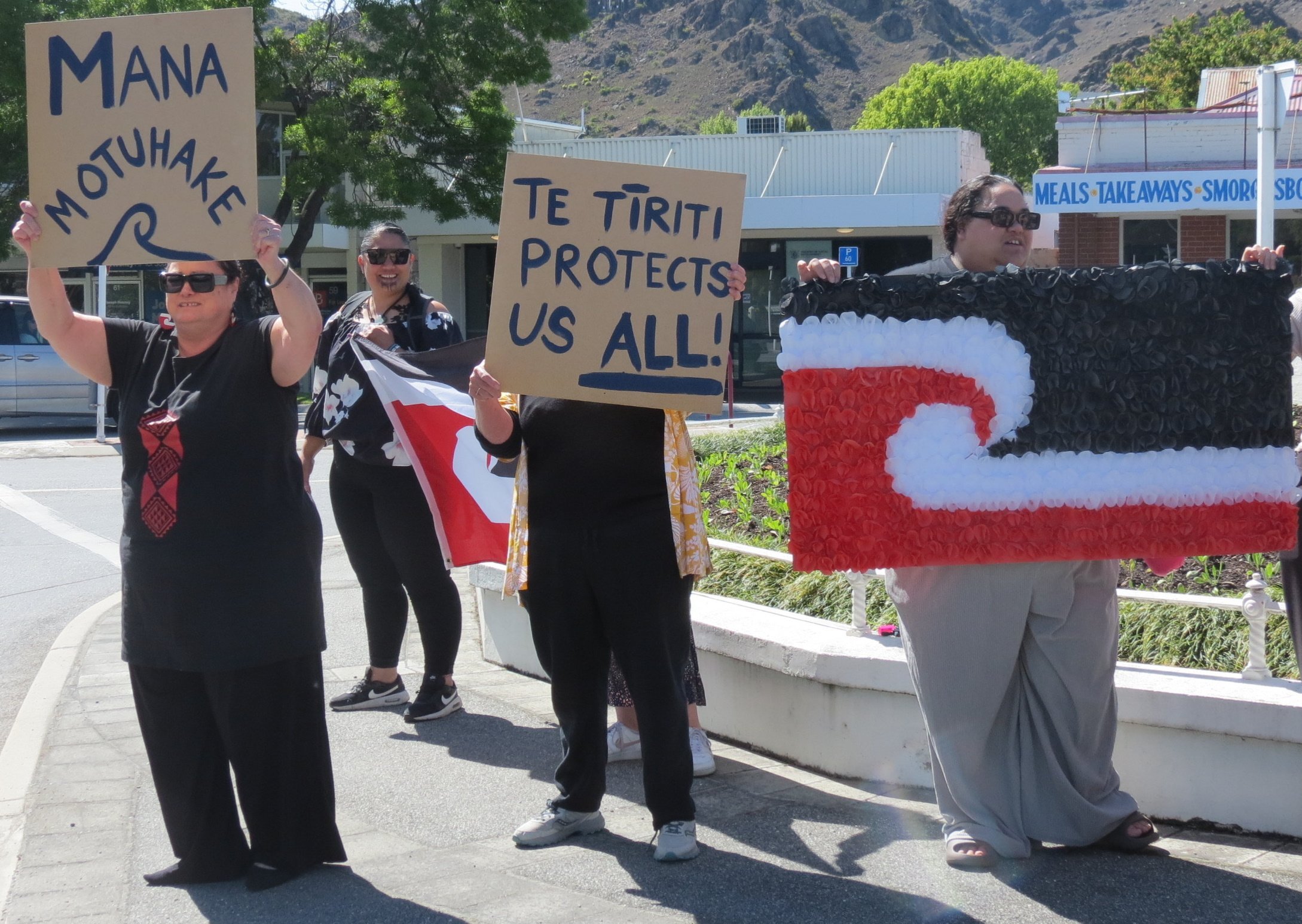 Frances Petuha (left) and other demonstrators with their signs. Petuha’s says ‘‘Self...