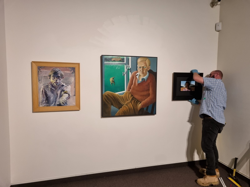 John Dennison hangs works for this month’s ‘‘Spotlight on the Permanent Collection’’ — three...