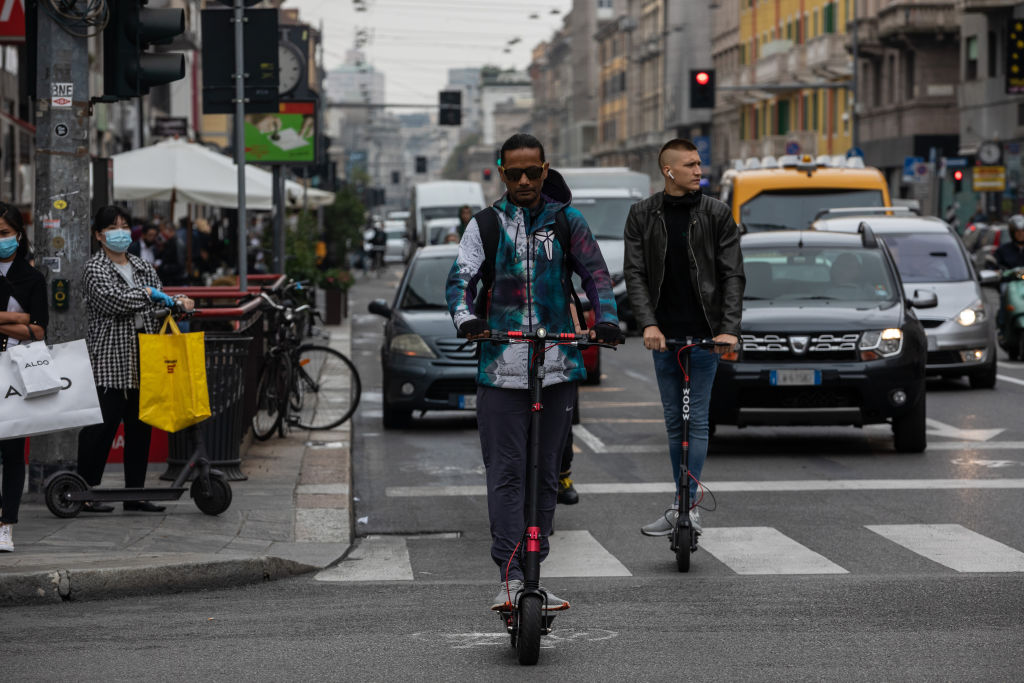 Two men ride their e-scooters through the traffic in Milan. Photo: Getty Images