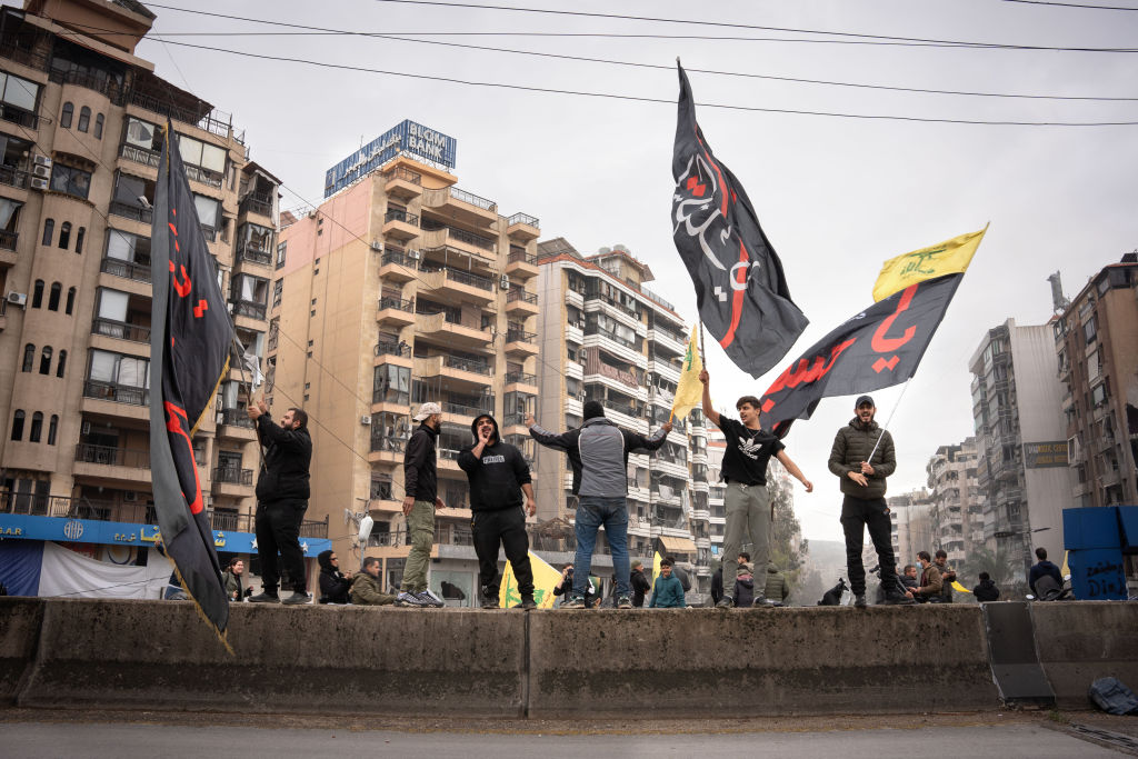 A group of men celebrate the ceasefire between Israel and Hezbollah, while waving Amal political...