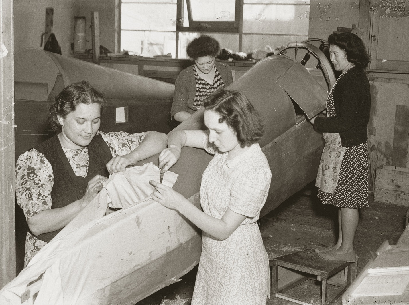 Workers at the Rongotai De Havilland factory sew fabric on to a Tiger Moth aircraft frame in 1943...