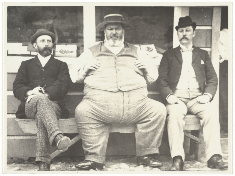 Michael Houlahan (centre) takes the weight off his feet in the company of two unidentified men....