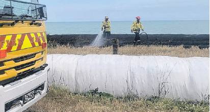 Firefighters extinguish the seaside grass fire at Pendarves. PHOTO: SUPPLIED

