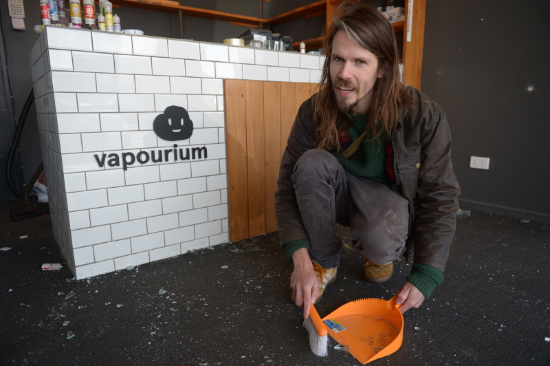 Vapourium South Dunedin manager Hamish Archer sweeps up broken glass after an early-morning smash...