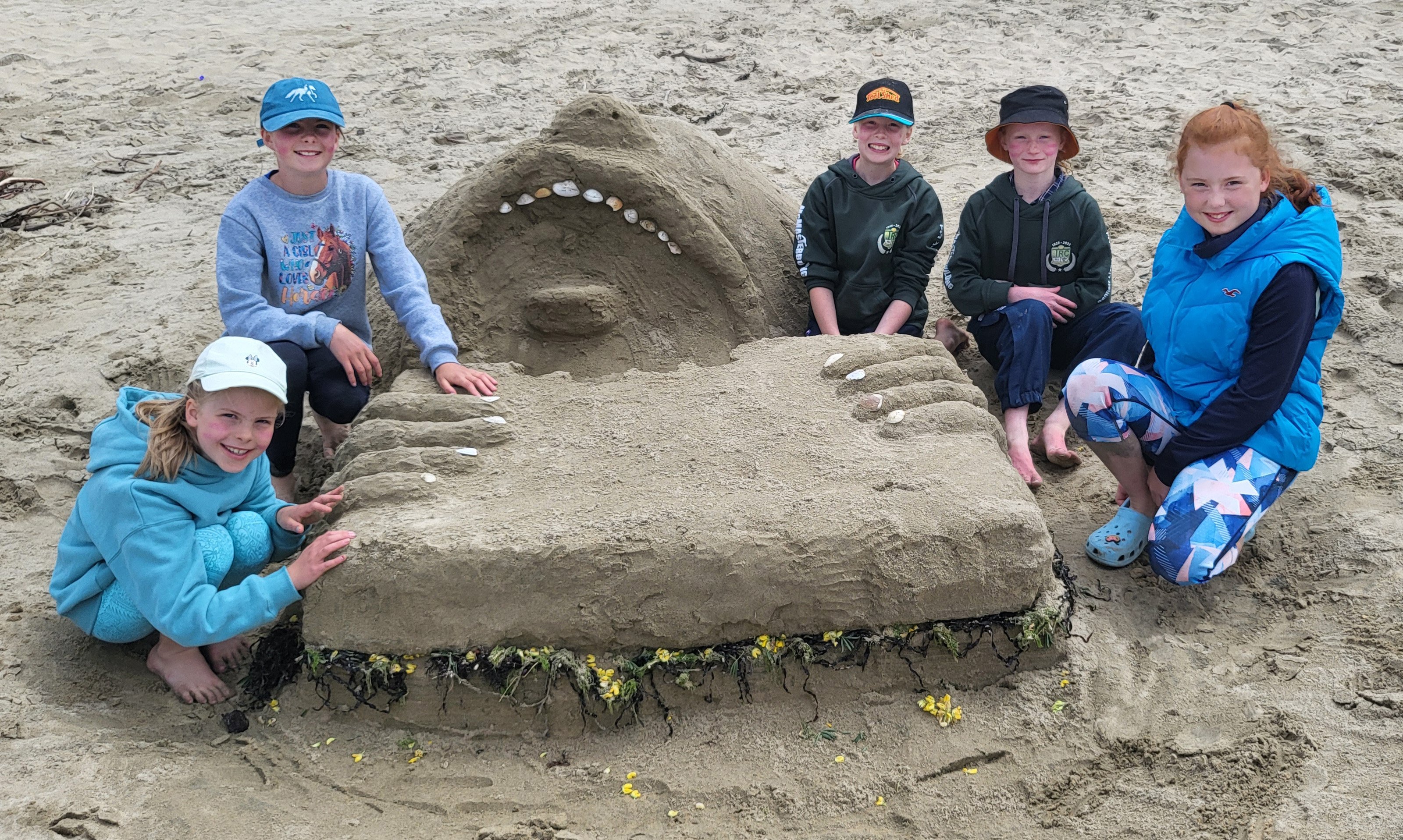 Sculpting a man eating a sandwich at the Curio Bay Big Dig on Saturday are (from left) Evelyn, 9,...