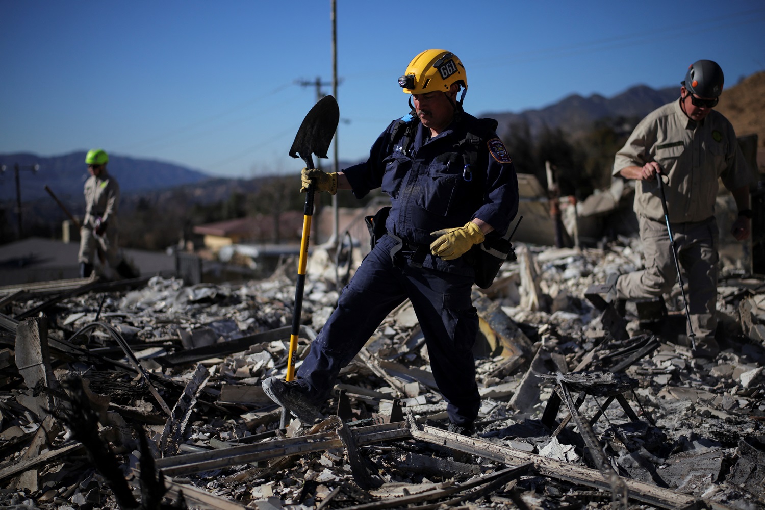 Search and rescue workers investigate the charred remains of a house, as the Eaton Fire continues...