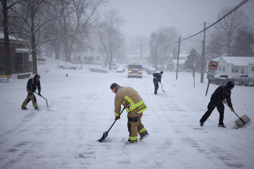 Firefighters from the Louisville Fire Department shovel snow in front of their station yesterday....