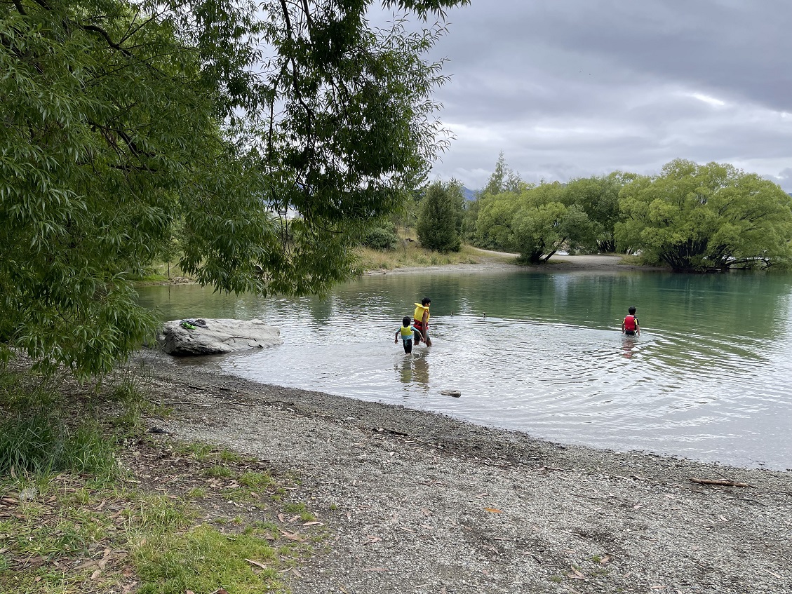 A visiting family take a swim in Lake Hāwea at the holiday park. Photo: Rawan Saadi