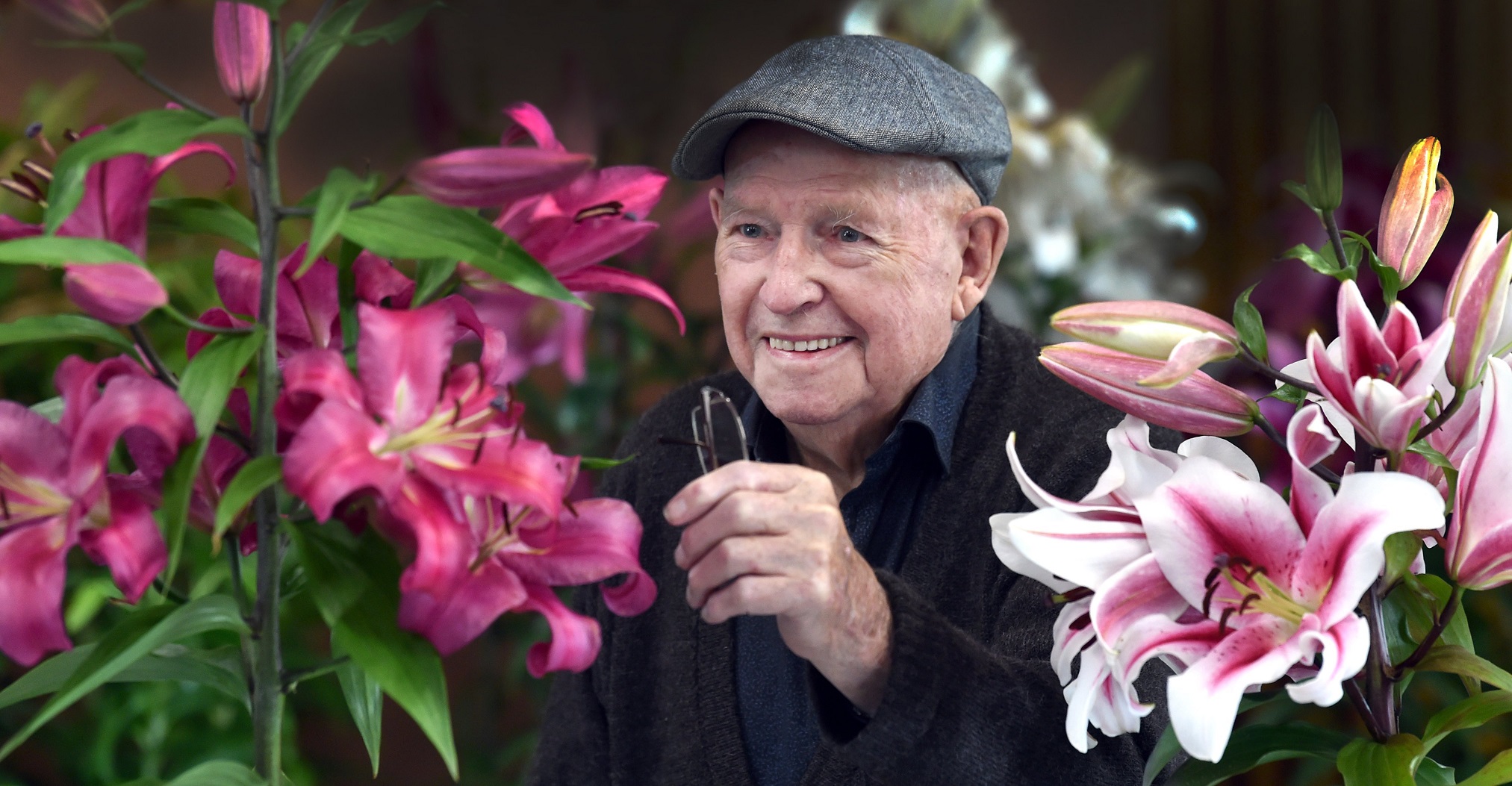 Ninety-four-year-old Bob Clark, of Timaru, checks out two lilies on show, a robina lily (left)...