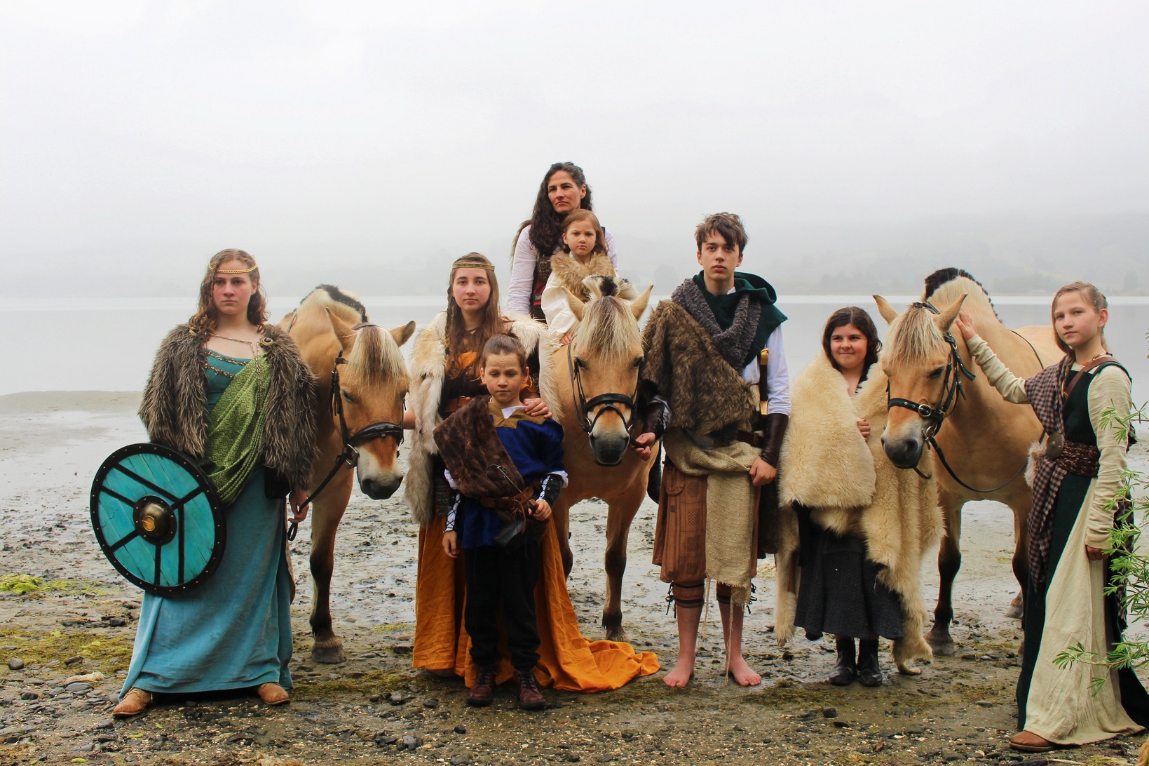 Young fans of the ancient Norwegian fjord horse breed pose in Viking garb with several horses at...