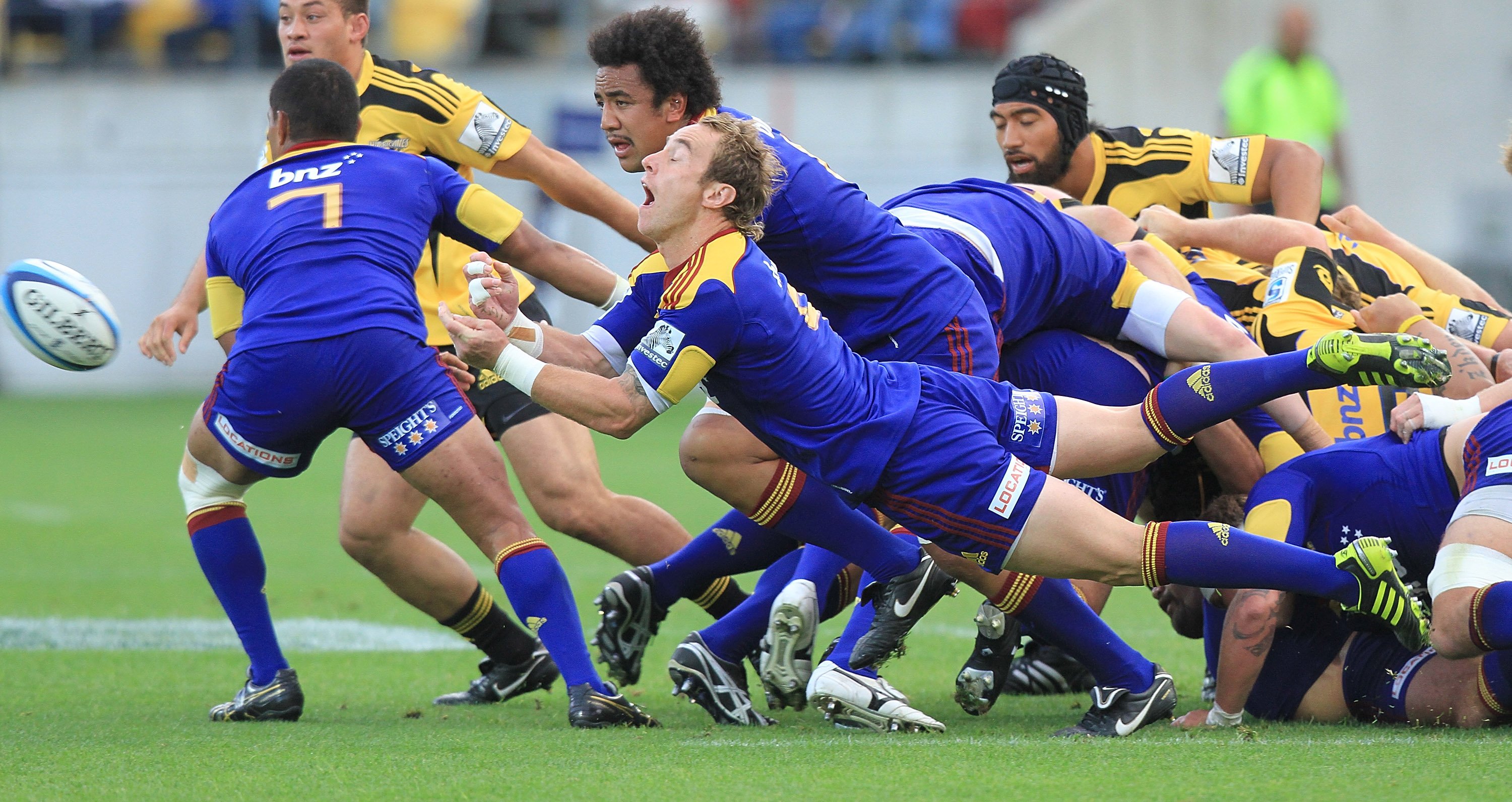 Highlanders halfback Jimmy Cowan fires out a no-look dive pass in front of loose forward team...