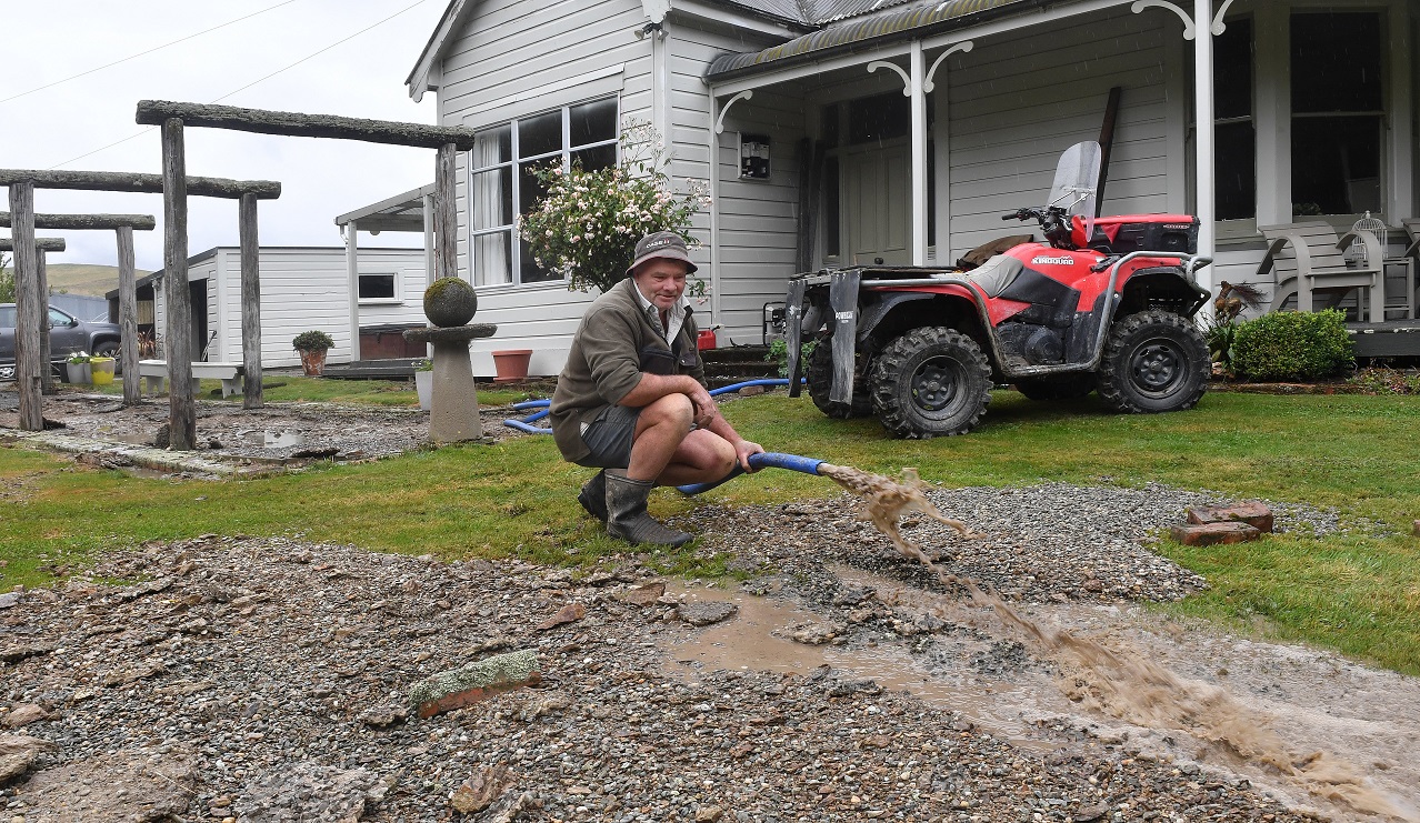 Beaumont resident Jamie Benington pumps floodwater from underneath his home after a river of...