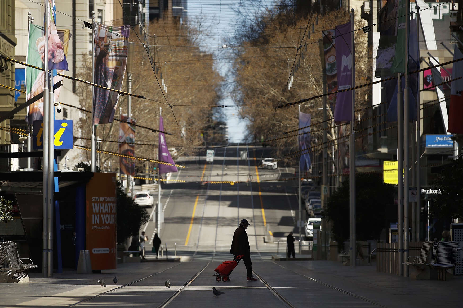 A person is seen walking across a quiet Bourke St during Covid lockdown in Melbourne. Photo:...