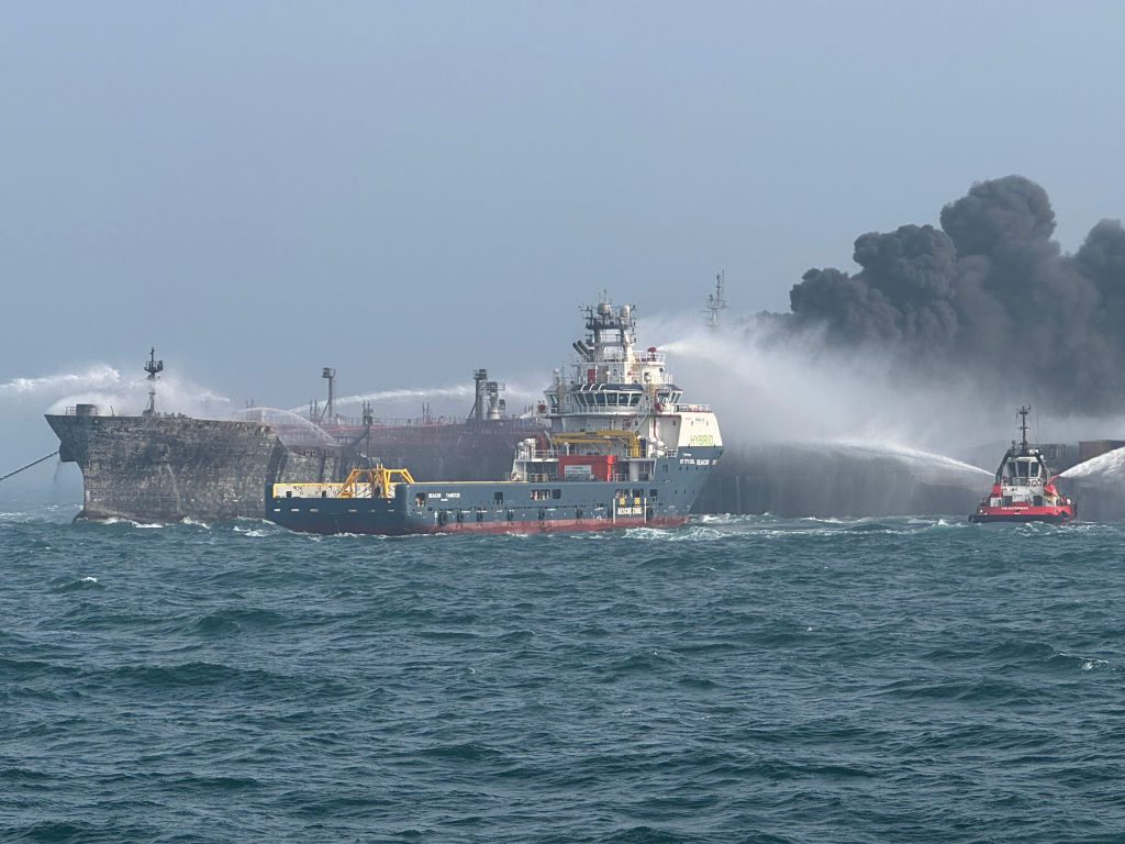 Fire and rescue services work to extinguish a fire after the crash between the ships off the...