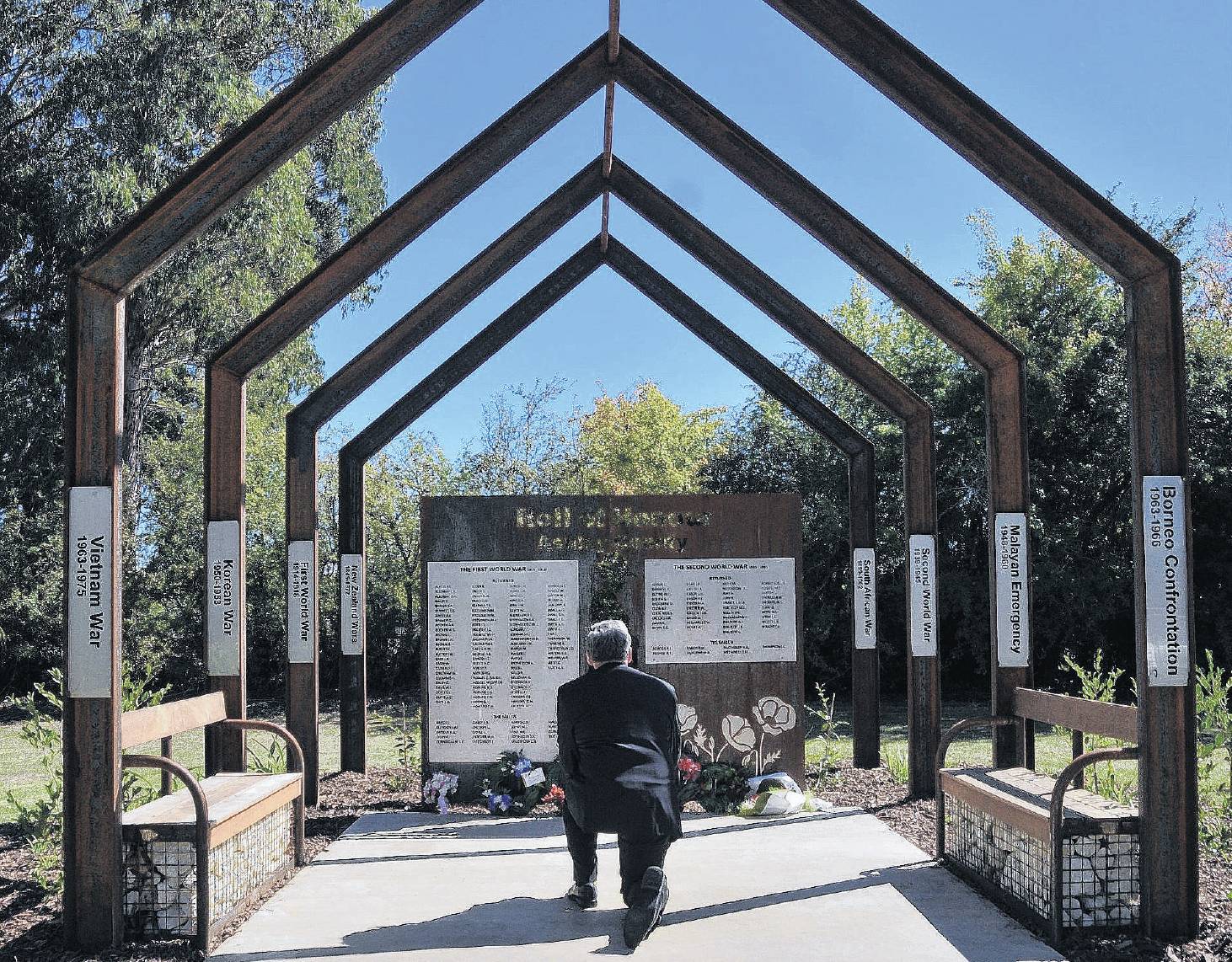 Rangiora-Ashley Community Board member Bruce McLaren kneels to take a photo of the wreaths laid...