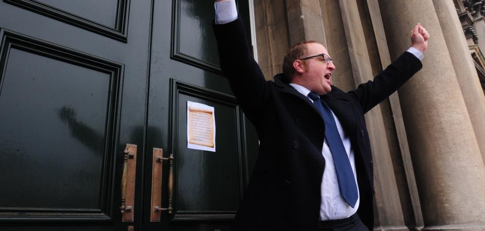 Victor Billot gestures after pinning a message to the doors of Dunedin’s Municipal Chambers as...