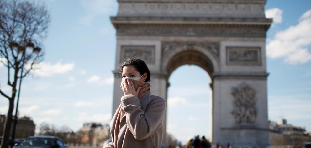 A woman wearing a protective mask, walks near Arc de Triomphe as France grapples with an outbreak of coronavirus. Photo: Reuters