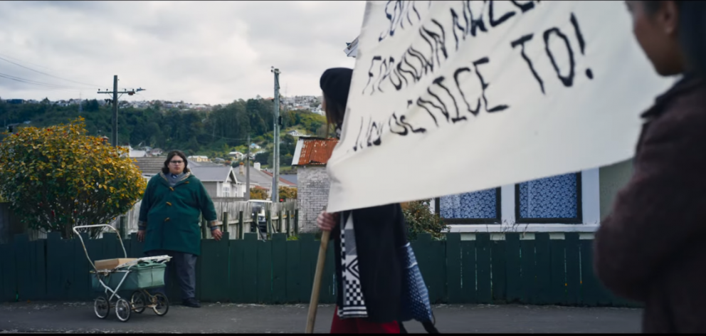 Julian Dennison watches a group of protestors march down a Dunedin street. 