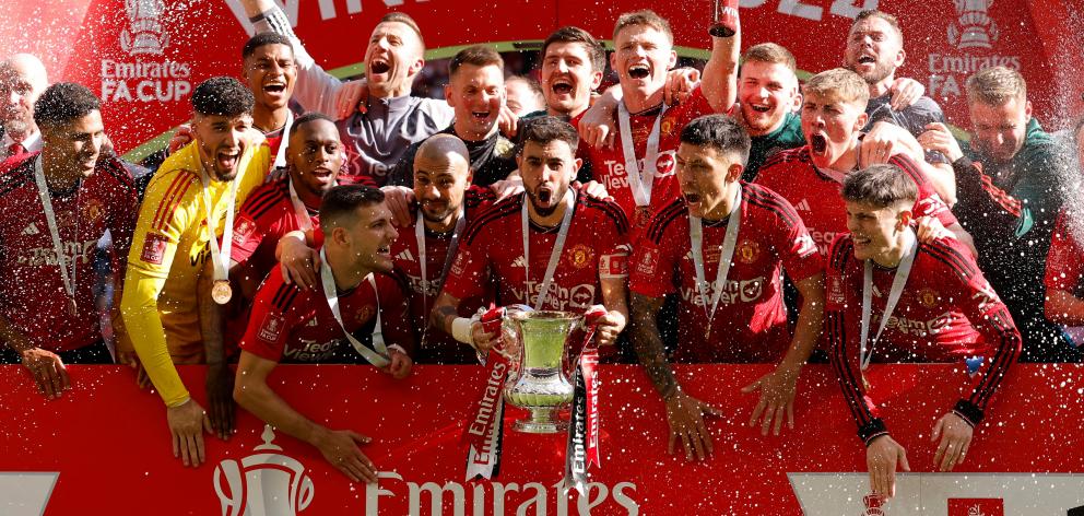 Manchester United's Bruno Fernandes celebrates with the trophy and teammates after winning the FA...