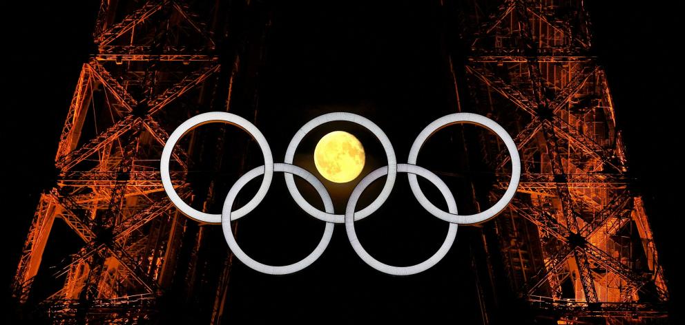 The moon makes an appearance through the Olympic rings on the Eiffel Tower in Paris. PHOTO: REUTERS